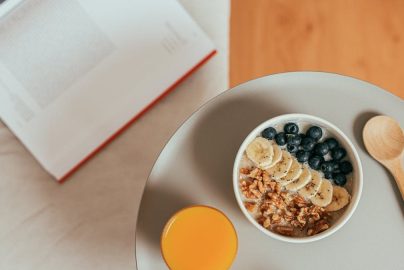 Top view of healthy breakfast with oatmeal, fresh fruit, and orange juice on a tray.